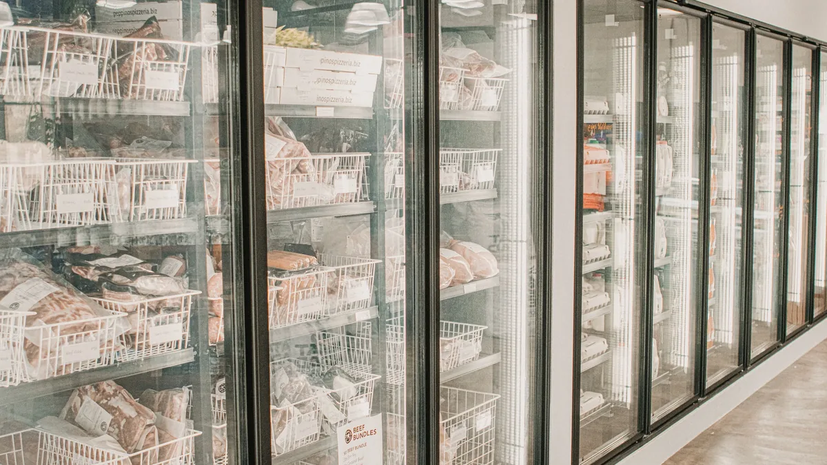 A row of glass-fronted freezers containing baskets of frozen food.