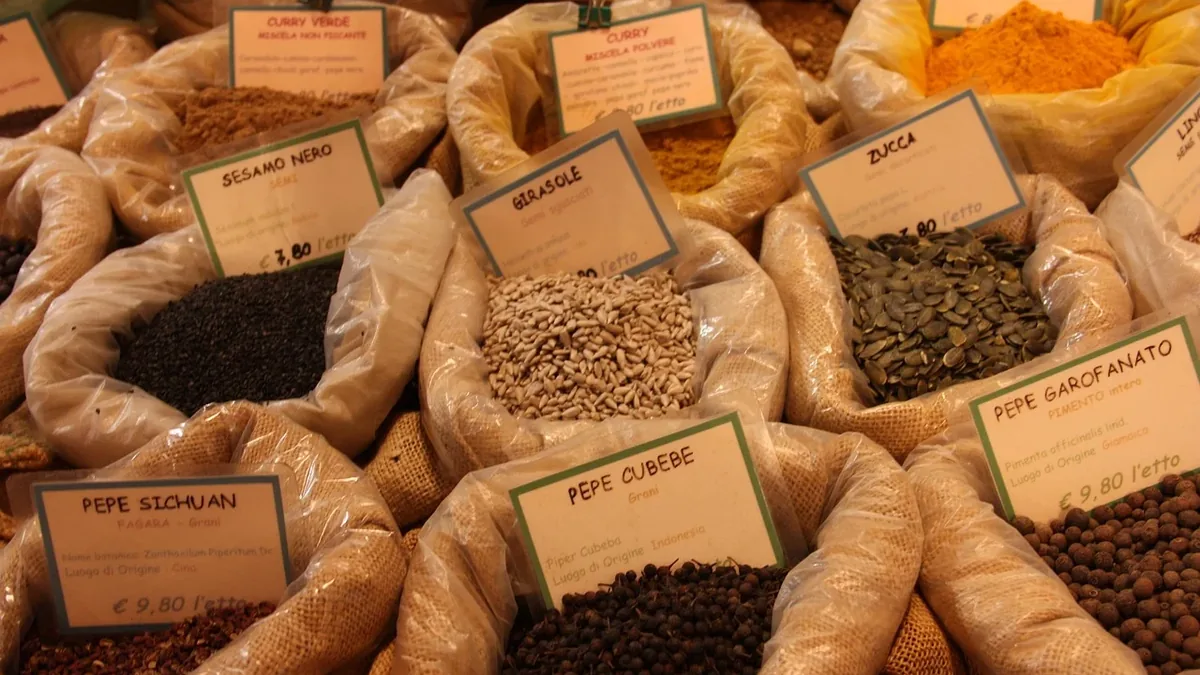 A collection of various spices and herbs in burlap sacks, each with a label attached.