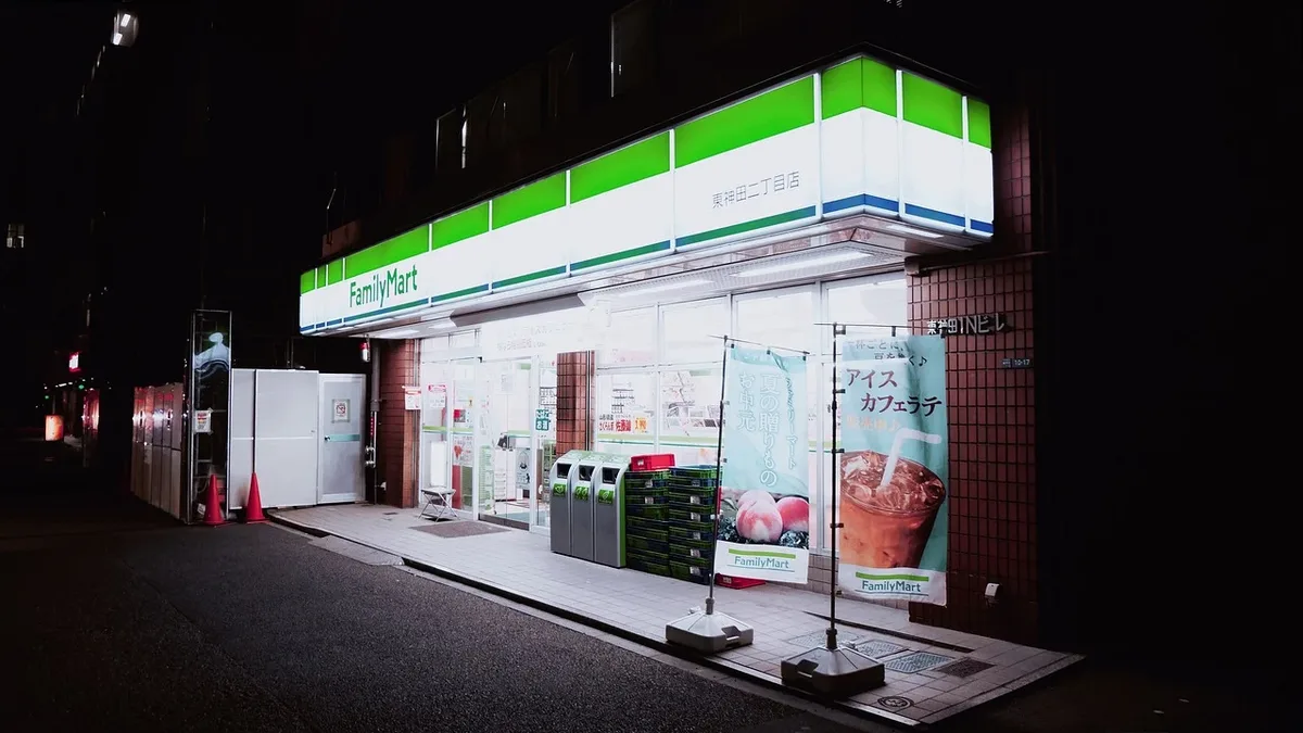 A FamilyMart convenience store at night, with a green and white sign above the entrance and a sidewalk in front.