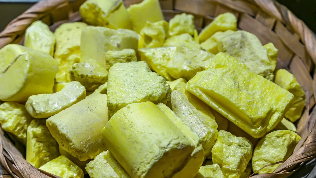 A basket filled with yellowish chunks of what appears to be butter or cheese, set against a dark background.