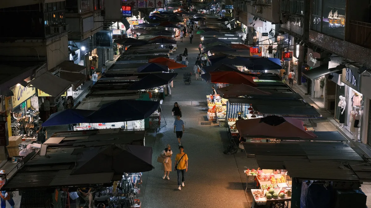 A bustling outdoor market at night, featuring numerous stalls and vendors.